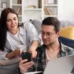 young couple looking at phone in living room